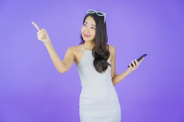 肖像画美しい若いアジアの女性が色の背景にスマート携帯電話で笑顔