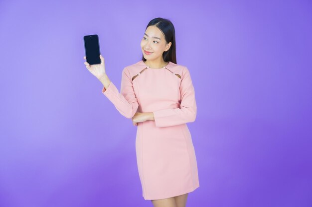 肖像画美しい若いアジアの女性が色の背景にスマート携帯電話で笑顔