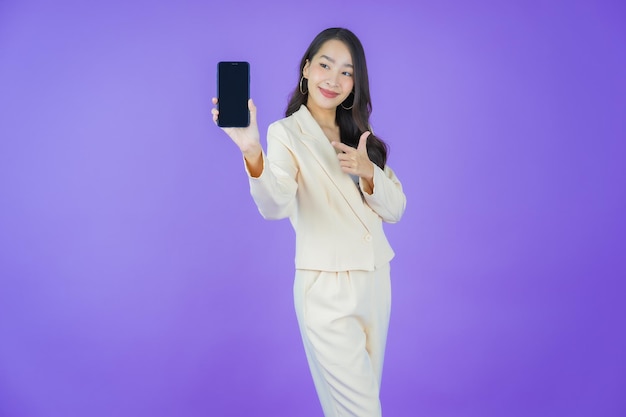 肖像画美しい若いアジアの女性が色の背景にスマート携帯電話で笑顔