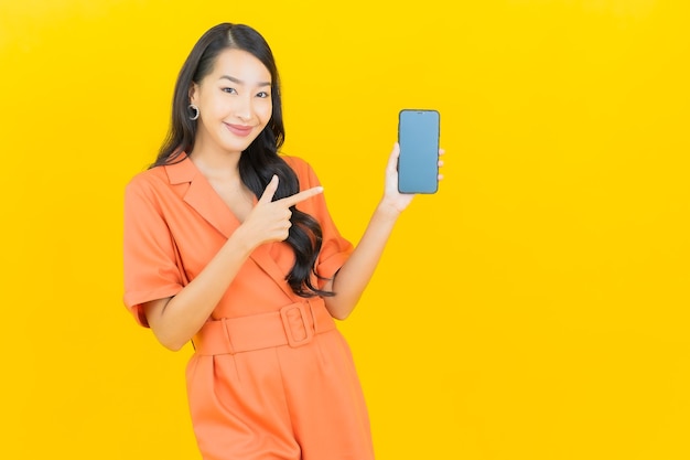 Portrait beautiful young asian woman smile with smart mobile phone on yellow