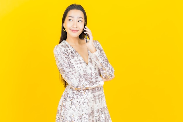 Portrait beautiful young asian woman smile with smart mobile phone on yellow