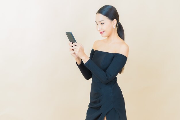 黄色のスマート携帯電話で笑顔美しい若いアジアの女性の肖像画