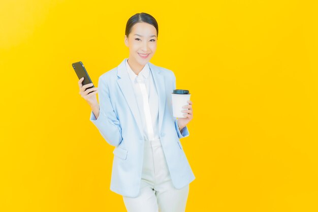 Portrait beautiful young asian woman smile with smart mobile phone on yellow