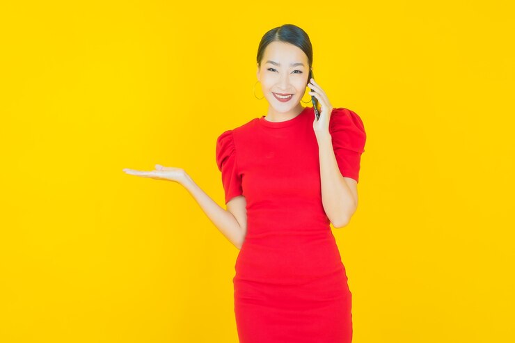 無料Photo 黄色のスマート携帯電話で笑顔美しい若いアジアの女性の肖像画