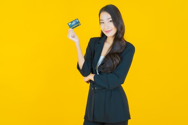 黄色のスマート携帯電話で笑顔美しい若いアジアの女性の肖像画