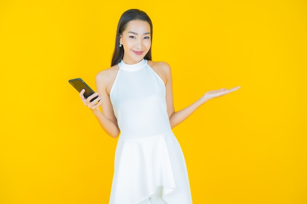 Portrait beautiful young asian woman smile with smart mobile phone on yellow