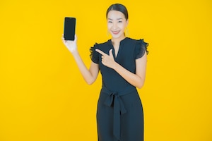 Portrait beautiful young asian woman smile with smart mobile phone on on yellow