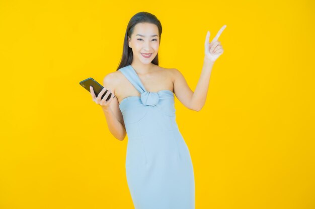 노란색 에 스마트 드폰 을 들고 미소 짓는 아름다운 젊은 아시아 여성 의 초상화