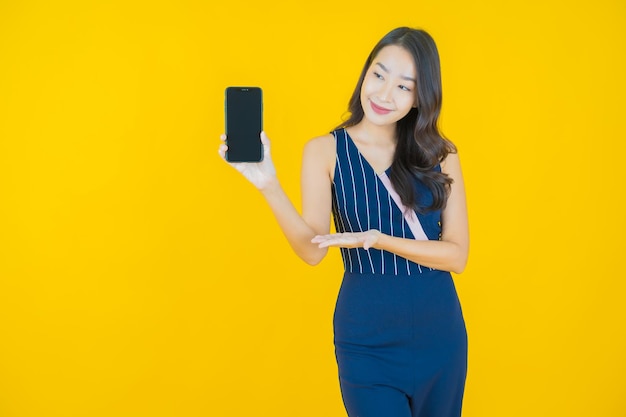 Улыбка женщины портрета красивая молодая азиатская с умным мобильным телефоном на