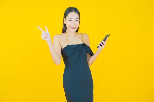 スマート携帯電話で美しい若いアジアの女性の笑顔の肖像画