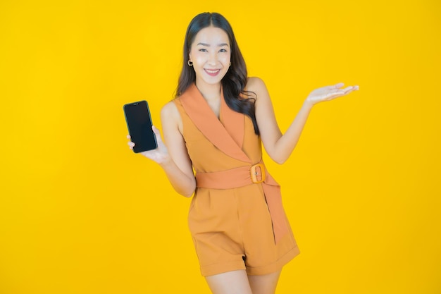 スマート携帯電話で美しい若いアジアの女性の笑顔の肖像画