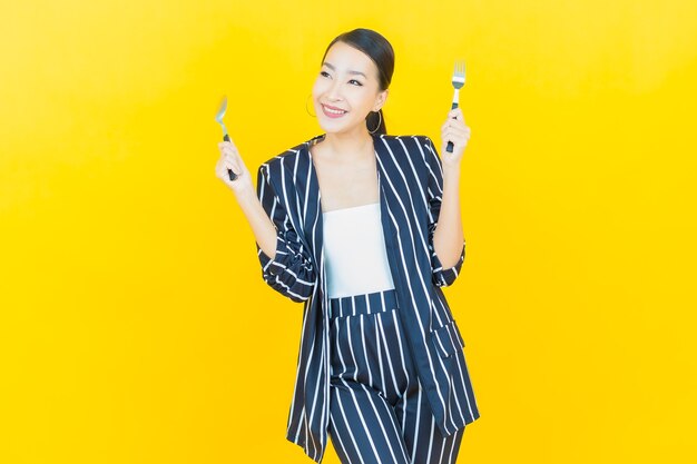 Portrait beautiful young asian woman smile with spoon and fork on color background