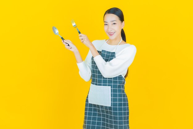 Portrait beautiful young asian woman smile with spoon and fork on yellow