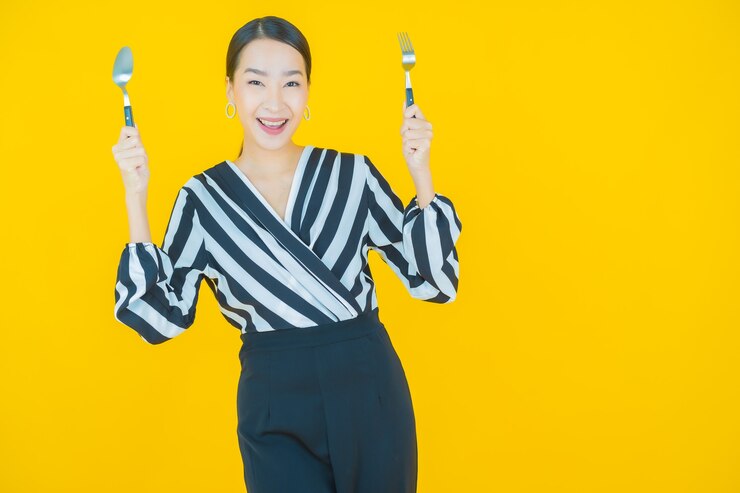 無料Photo 黄色のスプーンとフォークで笑顔美しい若いアジアの女性の肖像画