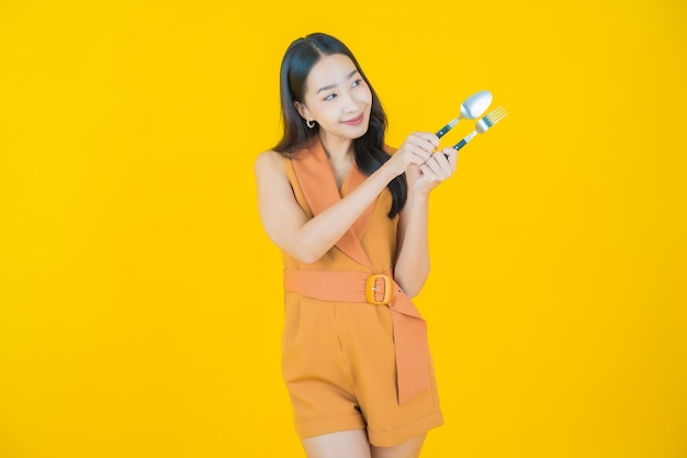 Portrait of beautiful  young asian woman smile with spoon and fork  