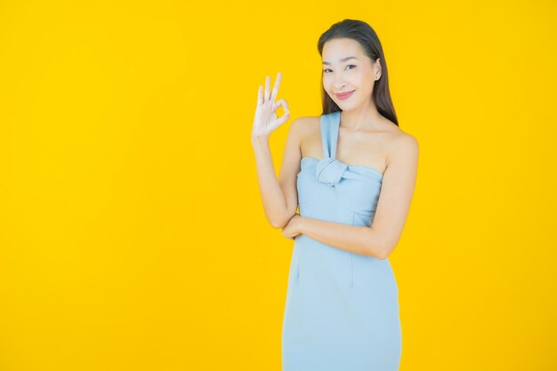 Улыбка женщины портрета красивая молодая азиатская на желтом