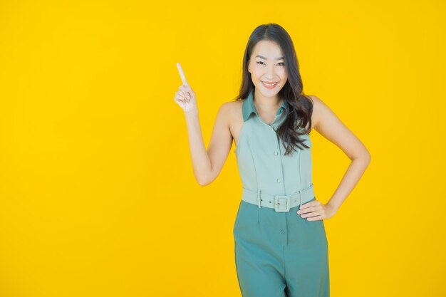 Portrait of beautiful young asian woman smiles doing action on yellow wall