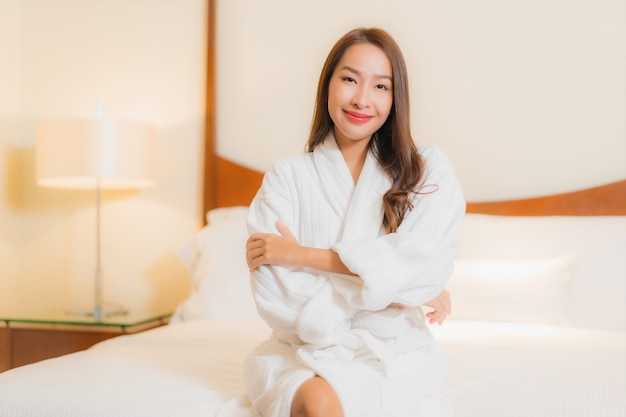Portrait beautiful young asian woman smiles relaxing on bed in bedroom interior