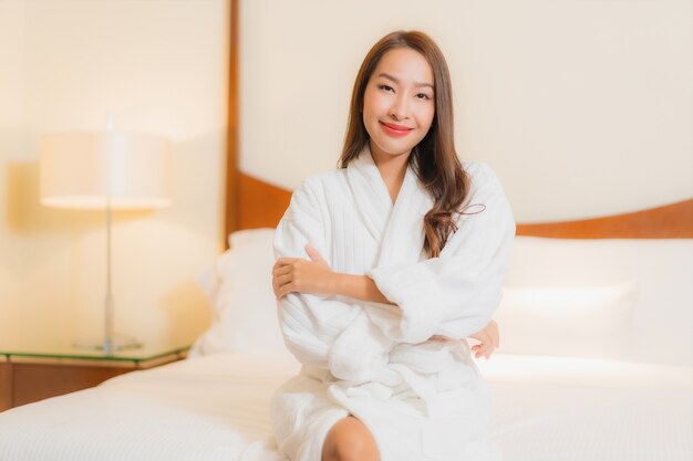 Улыбка женщины портрета красивая молодая азиатская ослабляя на кровати в интерьере спальни