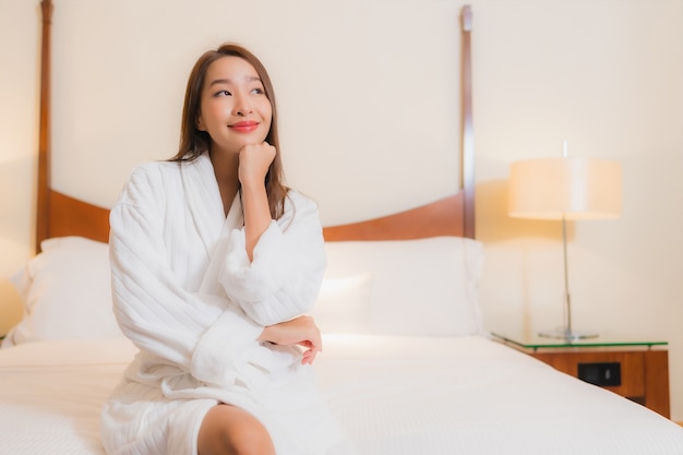 Portrait beautiful young asian woman smiles relaxing on bed in bedroom interior