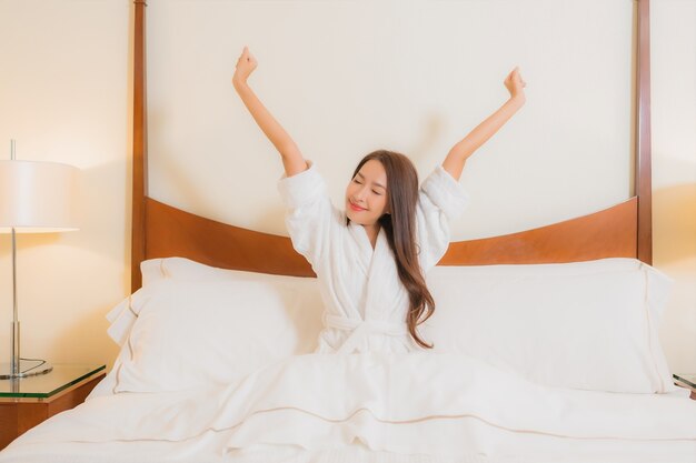 Portrait beautiful young asian woman smiles relaxing on bed in bedroom interior