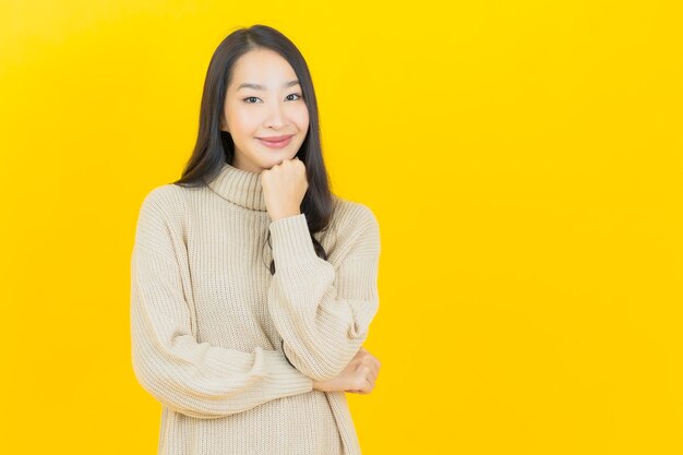 노란색 벽에 조치와 초상화 아름 다운 젊은 아시아 여자 미소