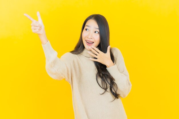 Portrait beautiful young asian woman smiles with action on yellow wall