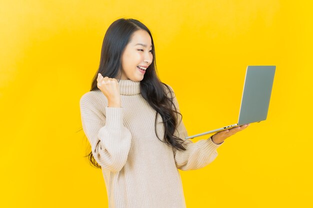 격리 된 배경에 컴퓨터 노트북과 세로 아름 다운 젊은 아시아 여자 미소