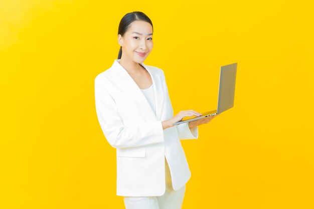 외진 벽에 컴퓨터 노트북을 들고 웃는 아름다운 젊은 아시아 여성 초상화