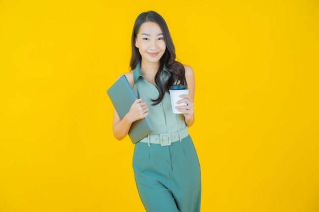 Portrait of beautiful young asian woman smiles with computer laptop on isolated wall