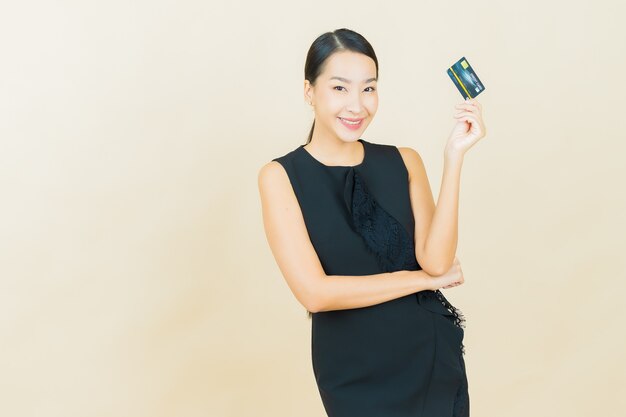 Portrait beautiful young asian woman smiles with credit card on color wall