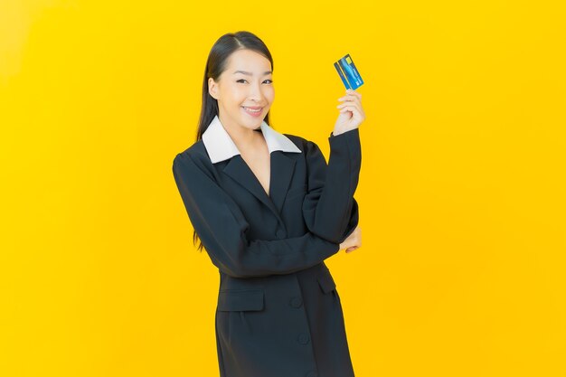 肖像画美しい若いアジアの女性が色の壁にクレジットカードで微笑む