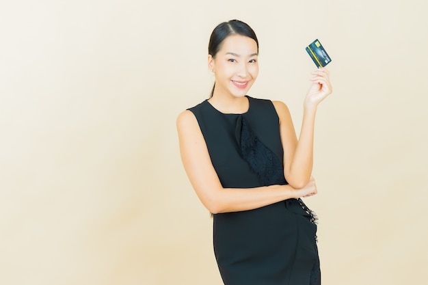 Бесплатное фото Улыбка женщины портрета красивая молодая азиатская с кредитной картой на стене цвета