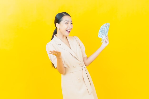 Portrait beautiful young asian woman smiles with a lot of cash and money on color wall