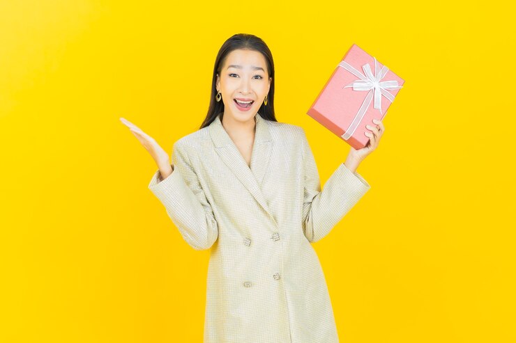 免費 Photo 美麗的年輕亞洲女人在彩色牆上微笑著紅色禮物盒的肖像