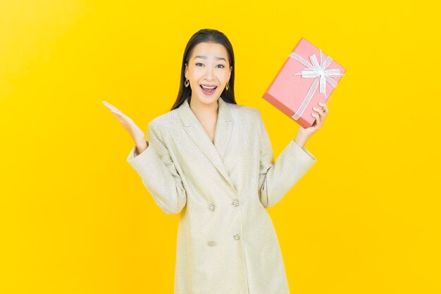 세로 아름 다운 젊은 아시아 여자 색 벽에 빨간색 선물 상자 미소