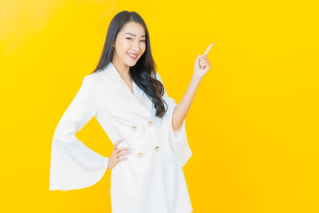 노란 벽에 웃는 아름다운 젊은 아시아 여성의 초상화