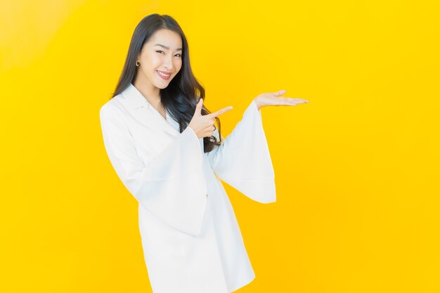 Портрет красивой молодой азиатской женщины улыбается на желтой стене