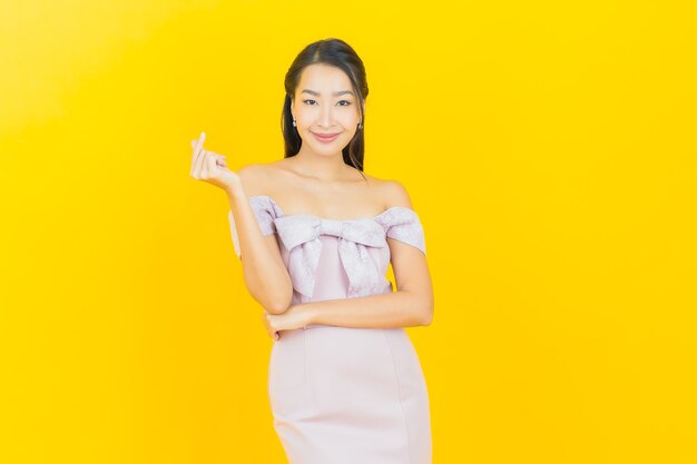 笑顔と色の壁にポーズをとって美しい若いアジア人女性
