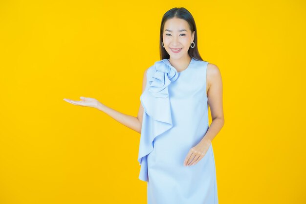 Женщина портрета красивая молодая азиатская, улыбаясь на желтом