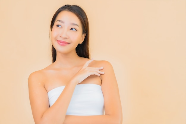 Bella giovane donna asiatica del ritratto nella stazione termale con trucco naturale sul beige
