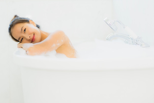 Женщина портрета красивая молодая азиатская принимает ванну в ванную