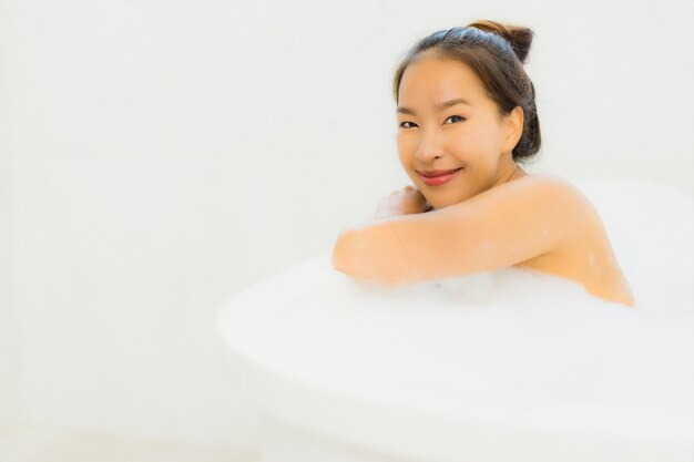 肖像画美しい若いアジア女性は浴室で浴槽を取る