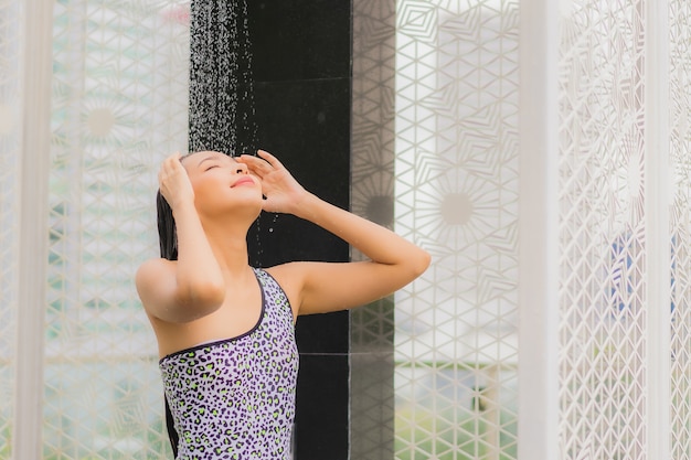 Foto gratuita la bella giovane donna asiatica del ritratto fa una doccia intorno alla piscina all'aperto