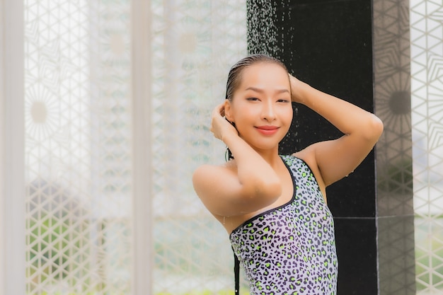 세로 아름 다운 젊은 아시아 여자 야외 수영장 주위에 샤워를