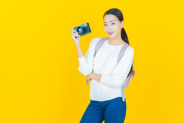 Portrait beautiful young asian woman use camera on yellow