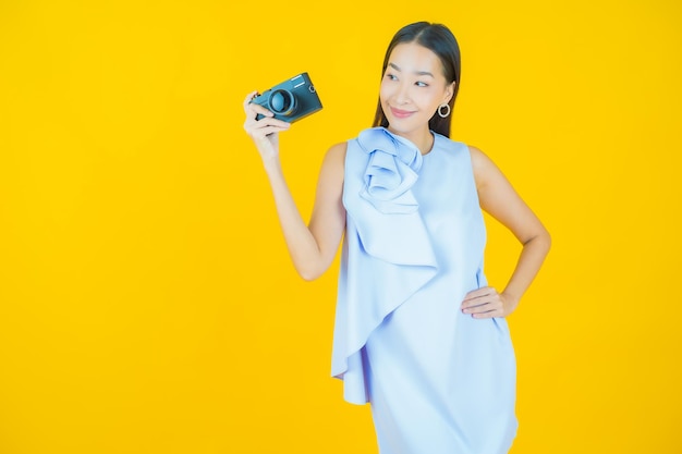 노란색에 카메라를 사용하는 아름다운 젊은 아시아 여성의 초상화