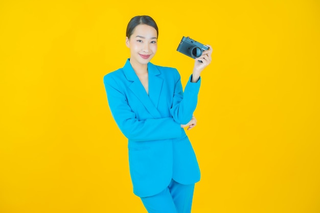 Portrait beautiful young asian woman use camera on yellow