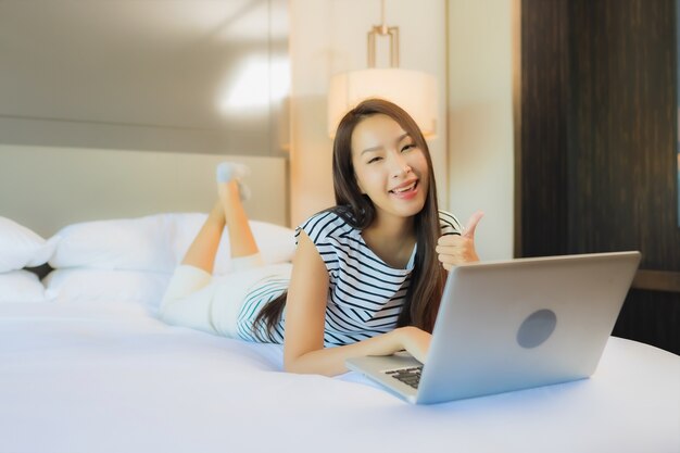 Portrait beautiful young asian woman use computer laptop on bed in bedroom interior