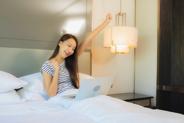 Portrait beautiful young asian woman use computer laptop on bed in bedroom interior